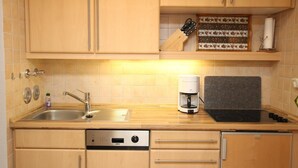A compact kitchen with a sink, a coffee maker, and a knife block on the countertop. - House by the sea app. 105 WB (Westerland)