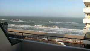 Un balcon avec vue sur la plage et l’océan.