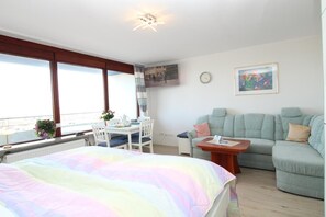 Een slaapkamer met een bed, een bureau, een stoel, een bank en een raam met uitzicht.