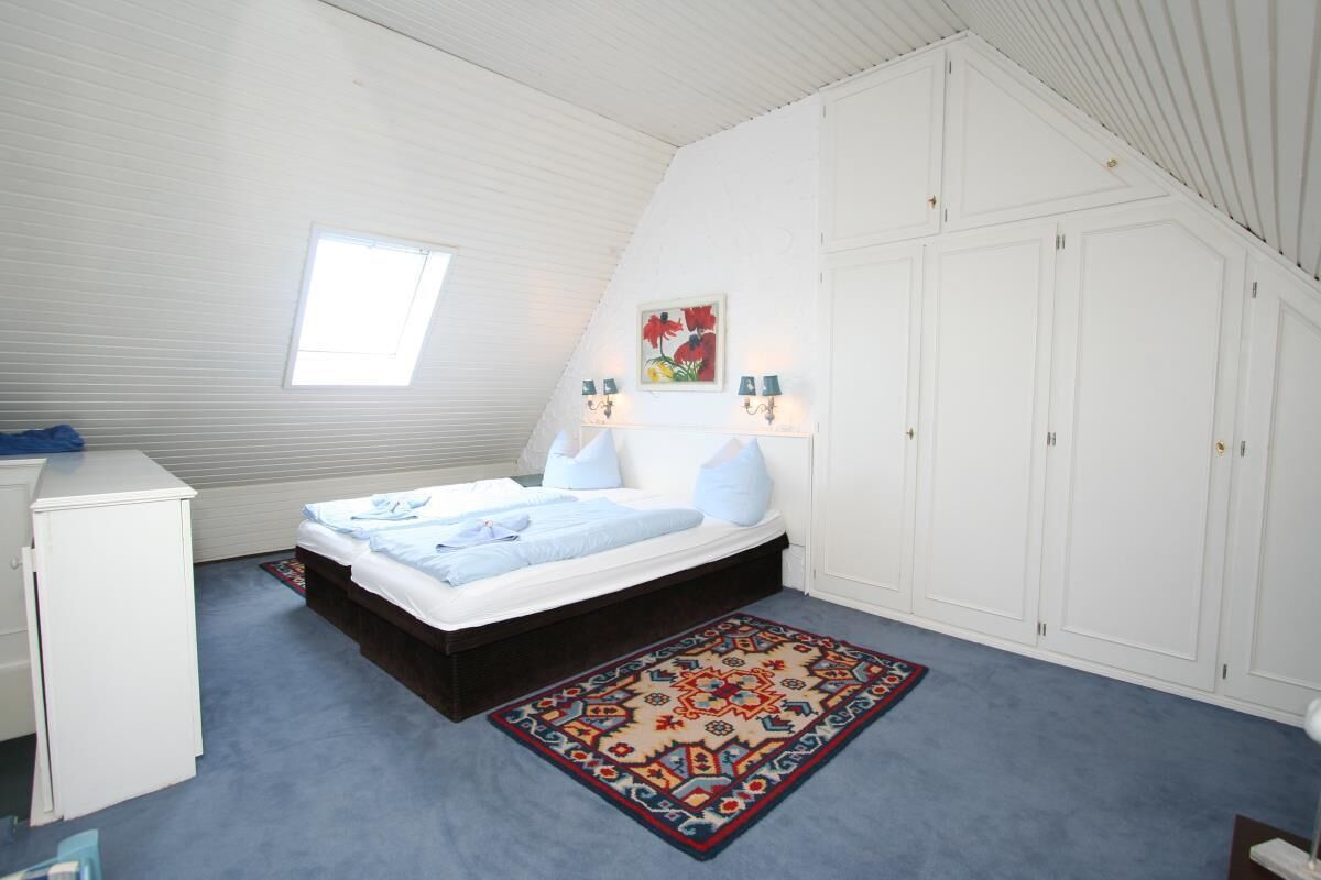 Un dormitorio con cama, escritorio, armario y ventana.