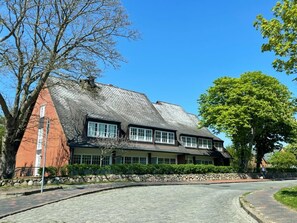 Traditional building with a steeply pitched roof, featuring a brick facade and large windows.