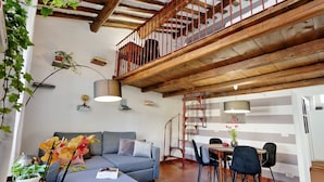 Ein gemütlicher Wohnbereich mit Sofa, Esstisch, Stühlen und einer Treppe mit Holzgeländer.