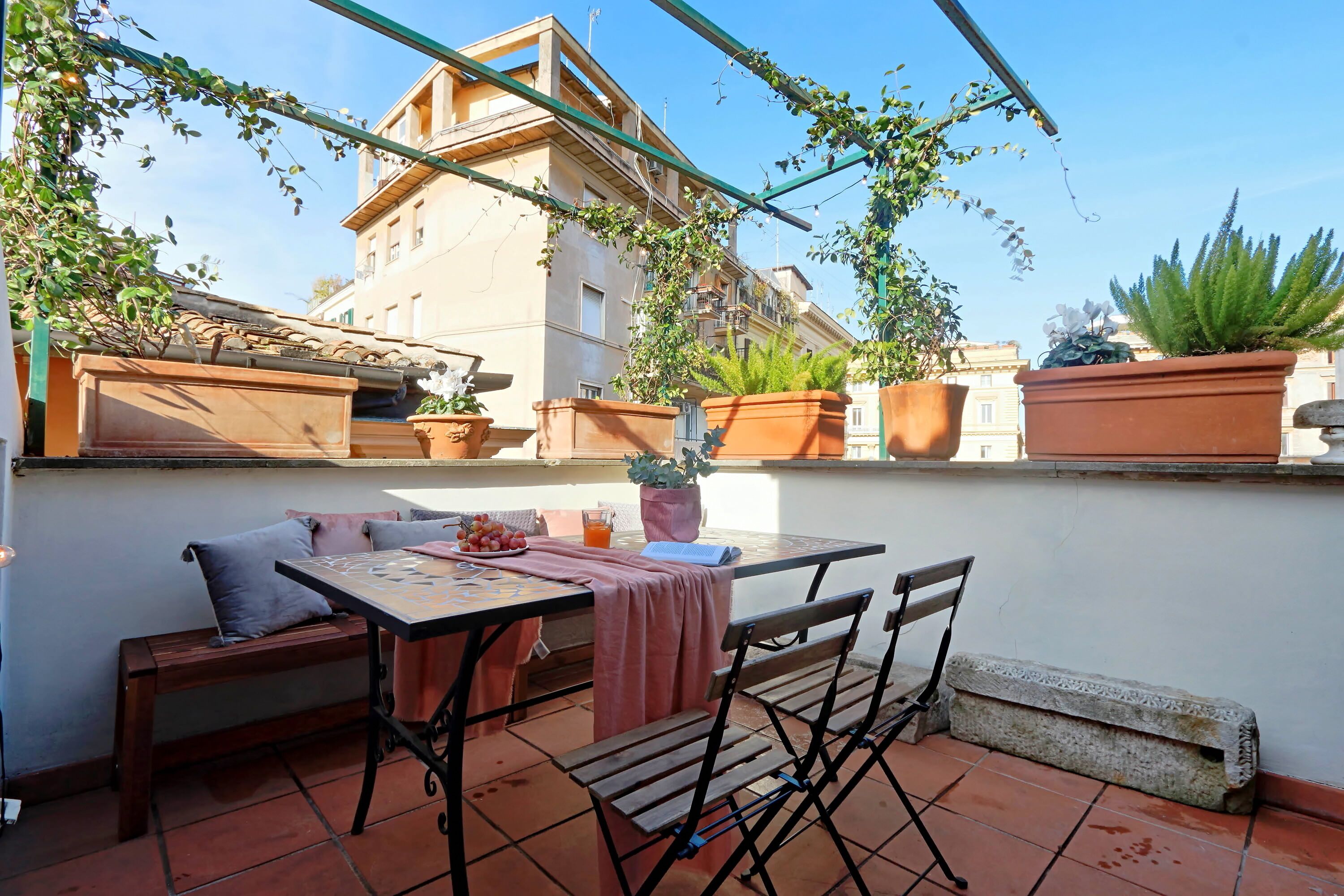 An outdoor patio with a table, chairs, and potted plants.
