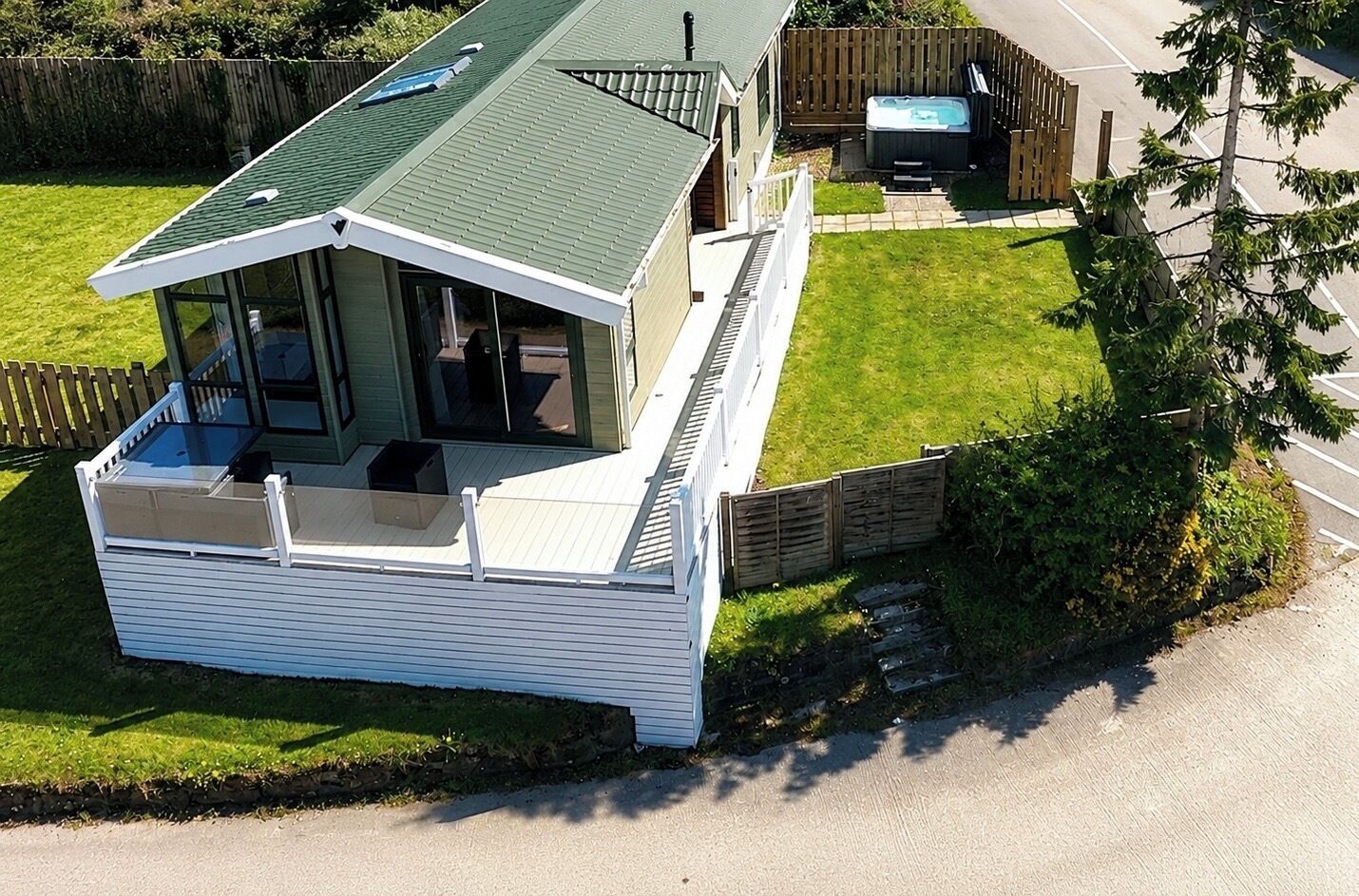A single-story house with a covered porch, a hot tub, and a fenced yard.