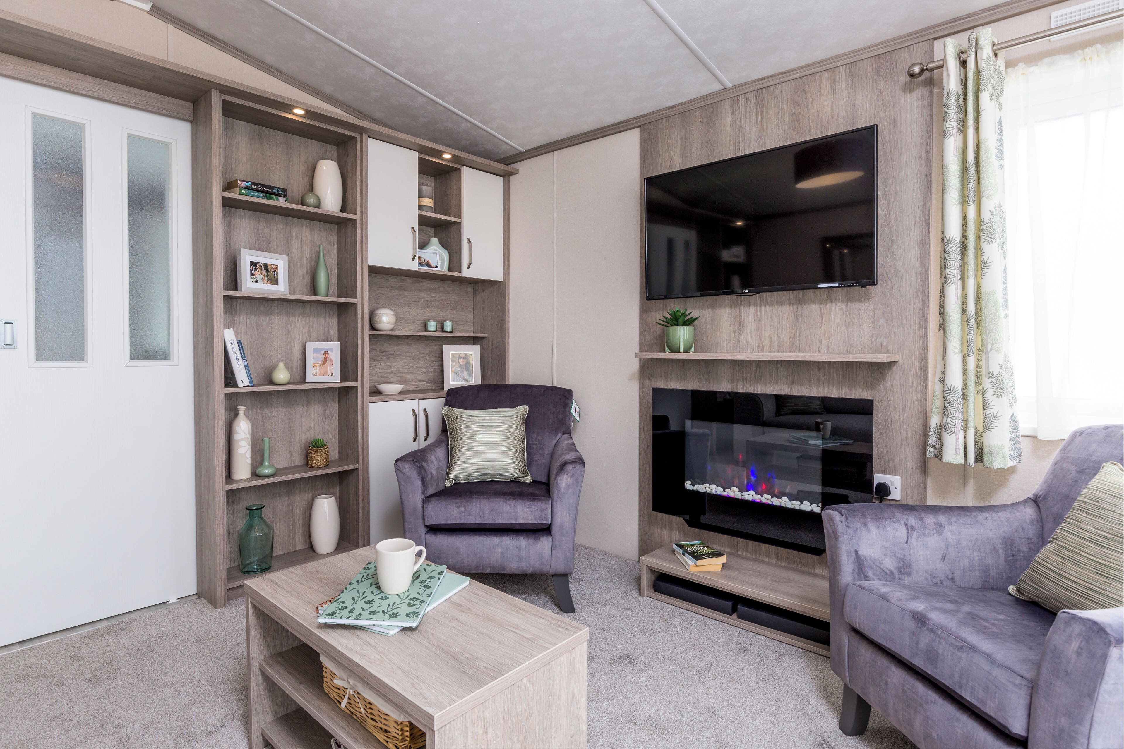 Ein Wohnzimmer mit Kamin, zwei Sesseln, einem Couchtisch und einem Bücherregal.
