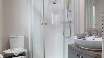 A modern bathroom with a glass-enclosed shower, a toilet, and a sink with a mirror above it.