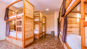 A room with bunk beds made of wood, a tiled floor, and a small trash bin. - Hostel Tarnopil (Ternopil)