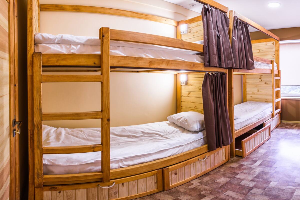 A bunk bed room with wooden frames, a window, and a patterned floor.