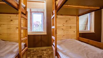 Une chambre avec un lit superposé en bois, une fenêtre et une porte.