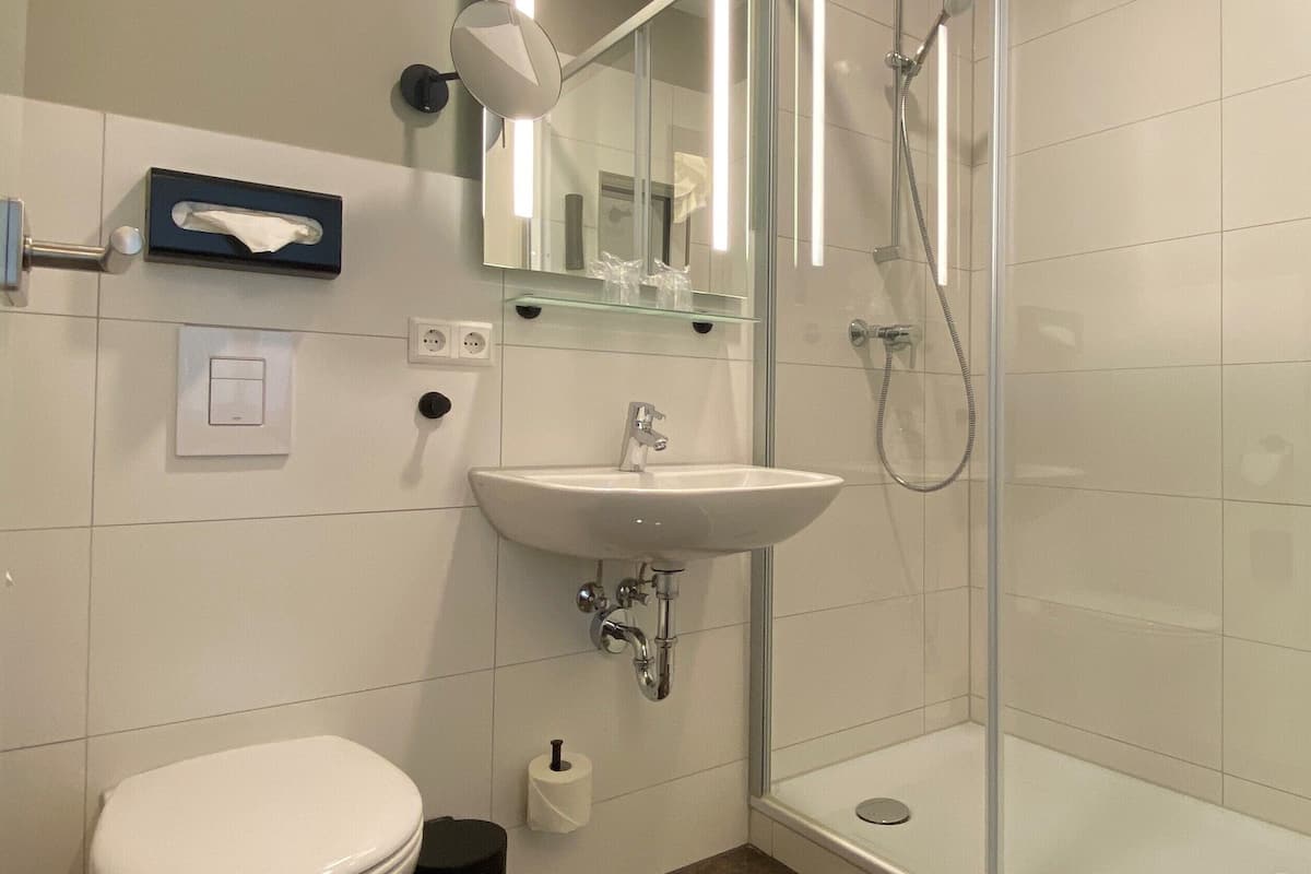A modern bathroom with a toilet, sink, and glass-enclosed shower.