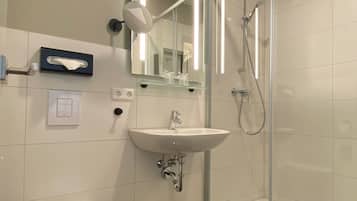 Un baño moderno con inodoro, lavabo y ducha con mampara de vidrio.