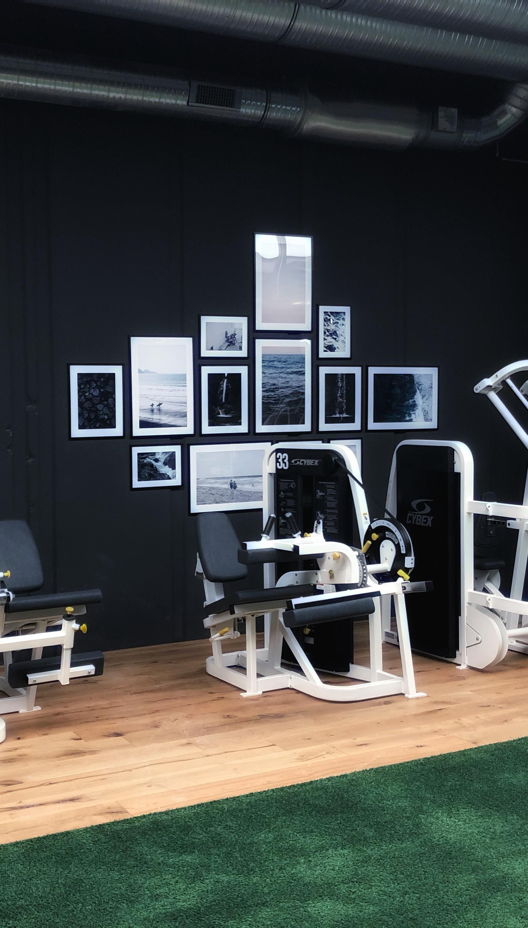 Ein Fitnessraum mit Trainingsgeräten und einer Wand, die mit gerahmten Bildern geschmückt ist.