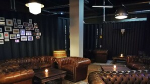 A lounge area with leather sofas, a wooden coffee table, and a barrel. - LOFTSTYLE Hotel Hannover, Best Western Signature Collection (Hannover)