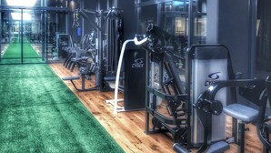 A gym with various exercise machines, a green carpet, and a wooden floor. - LOFTSTYLE Hotel Hannover, Best Western Signature Collection (Hannover)