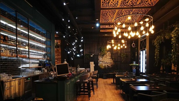 A restaurant interior with a bar area, wooden flooring, and hanging light fixtures. - LOFTSTYLE Hotel Hannover, Best Western Signature Collection (Hannover)