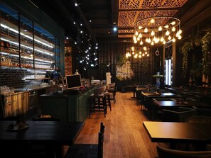 A restaurant interior with a bar area, wooden flooring, and hanging light fixtures. - LOFTSTYLE Hotel Hannover, Best Western Signature Collection (Hannover)