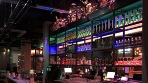 A bar area with shelves of bottles, a bar counter, and bar stools. - LOFTSTYLE Hotel Hannover, Best Western Signature Collection (Hannover)