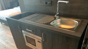 A compact kitchen with a built-in oven, a sink, and a stovetop. - LOFTSTYLE Hotel Hannover, Best Western Signature Collection (Hannover)