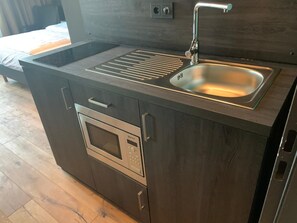 A compact kitchen with a built-in oven, a sink, and a stovetop. - LOFTSTYLE Hotel Hannover, Best Western Signature Collection (Hannover)