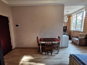 A dining area with a table and chairs, a sofa, and a kitchen area with a window.