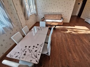 A dining area with a wooden table and chairs, a sofa, and a patterned wallpaper.