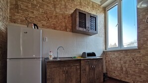 Uma cozinha com geladeira, armários de madeira, micro-ondas e janela com vista.