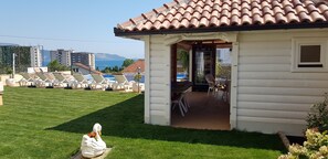 Ein weißes Gebäude mit einem Ziegeldach, einer Terrasse mit Lounge-Möbeln und Blick auf das Meer.