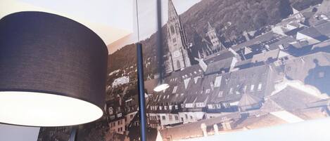 A room with a large window overlooking a town with historic buildings and a church spire.