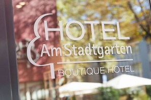 A hotel sign with the name "HOTEL Am Stadtgarten" and "BOUTIQUE HOTEL" written on it. - Boutiquehotel am Stadtgarten (Freiburg im Breisgau)