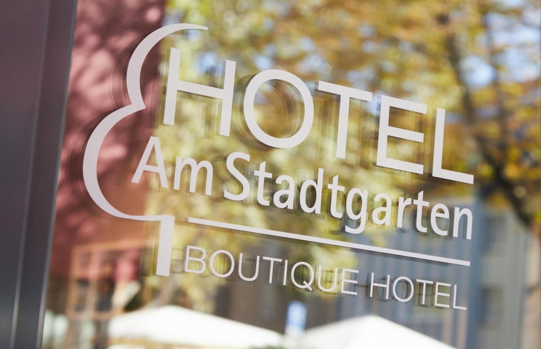 Une enseigne d’hôtel portant le nom « HOTEL Am Stadtgarten » et les mots « HÔTEL-BOUTIQUE » en dessous.