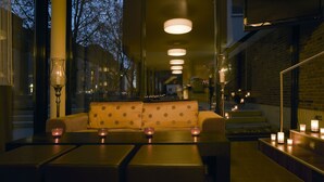 A dimly lit interior with a sofa and tables, candles, and a brick wall. - Boutiquehotel am Stadtgarten (Freiburg im Breisgau)