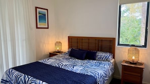 Una camera da letto con un letto, due comodini, una finestra e un quadro appeso al muro.