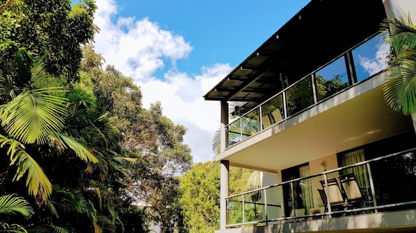 Un edificio moderno su due piani, con ampie finestre e un balcone, immerso nel verde.