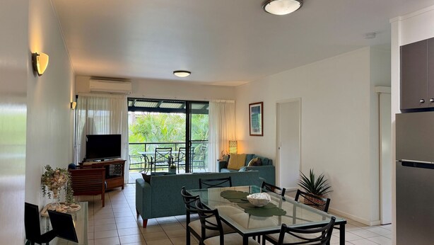 A modern living room with a television, sofa, and dining area.