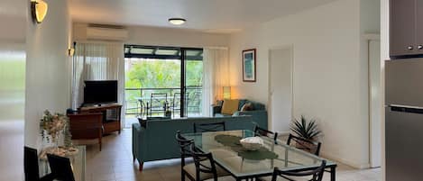 A modern living room with a television, sofa, and dining area.