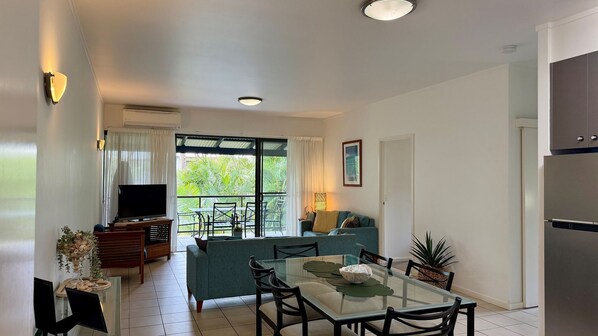 A modern living room with a television, sofa, and dining area.