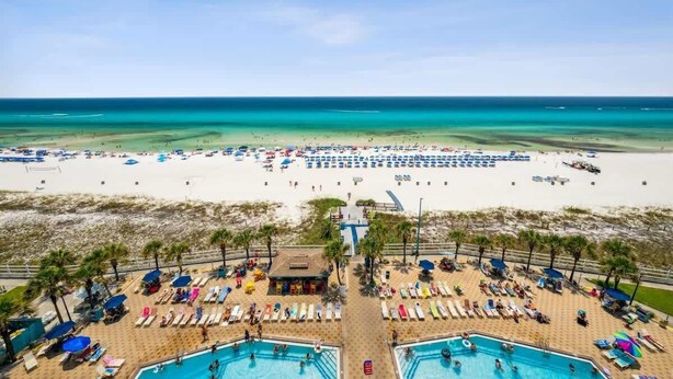 Un complexe hôtelier de bord de mer doté de deux piscines, de chaises longues et de parasols.