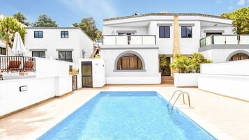 Een buitenzwembad, ligstoelen bij het zwembad