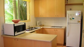 Cocina compacta con microondas, pileta y refrigerador.