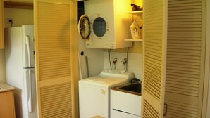 Una cocina compacta con refrigerador, lavadora y pileta.