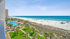 A beach resort with a swimming pool, palm trees, and a view of the ocean.