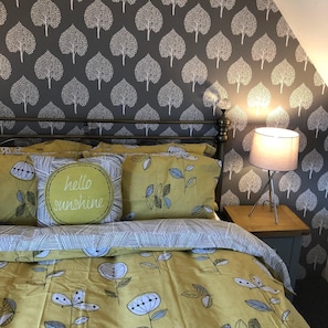 Relax in a nature-inspired retreat with a bed adorned with a floral-patterned bedspread and a tree-patterned headboard.