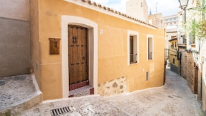 A narrow street with a building featuring a large wooden door and small windows.
