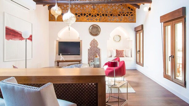 A spacious living area with a wooden dining table, a red chair, a TV, and decorative wall art.