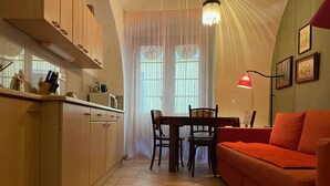 Uma cozinha compacta com mesa e cadeiras, um sofá vermelho e um tapete estampado.