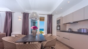 A modern kitchen with a dining area, featuring a table and chairs, a pendant light, and a view of the sea. - Villa Diva with 7 bedrooms, heated pool, sauna and fun zone, sea views (Podstrana)