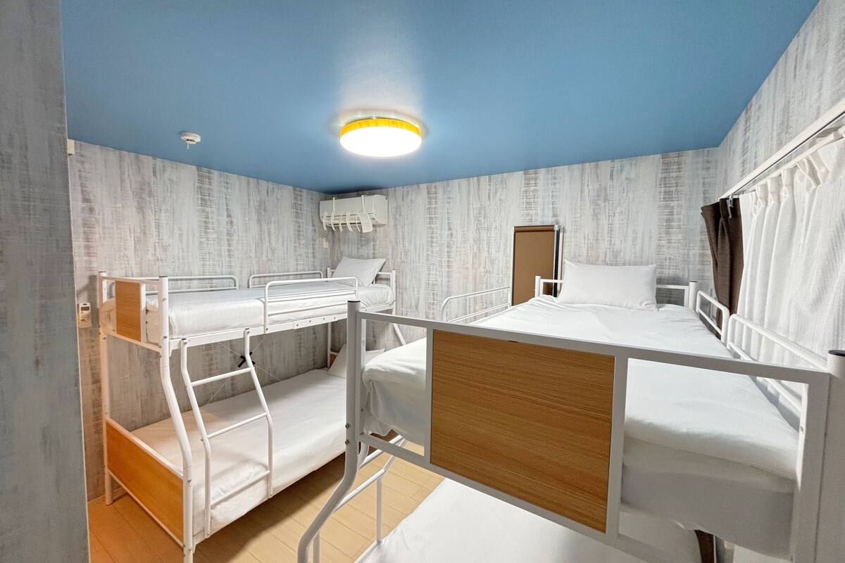 A bunk bed room with a wooden headboard, a ceiling light, and a door.