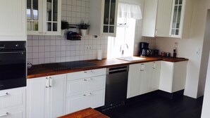 A modern kitchen with white cabinetry, a wooden countertop, and a black dishwasher.