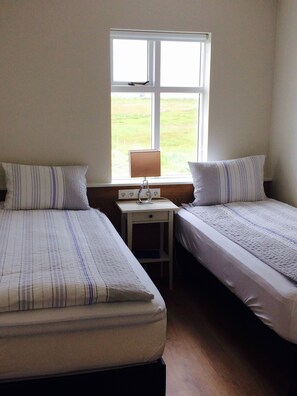 Un dormitorio con dos camas, una mesita de noche y una ventana con vistas a un campo cubierto de hierba.