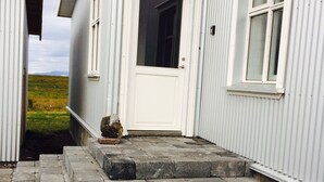 A white building with a white door and a small window. There are stone steps leading up to the door.